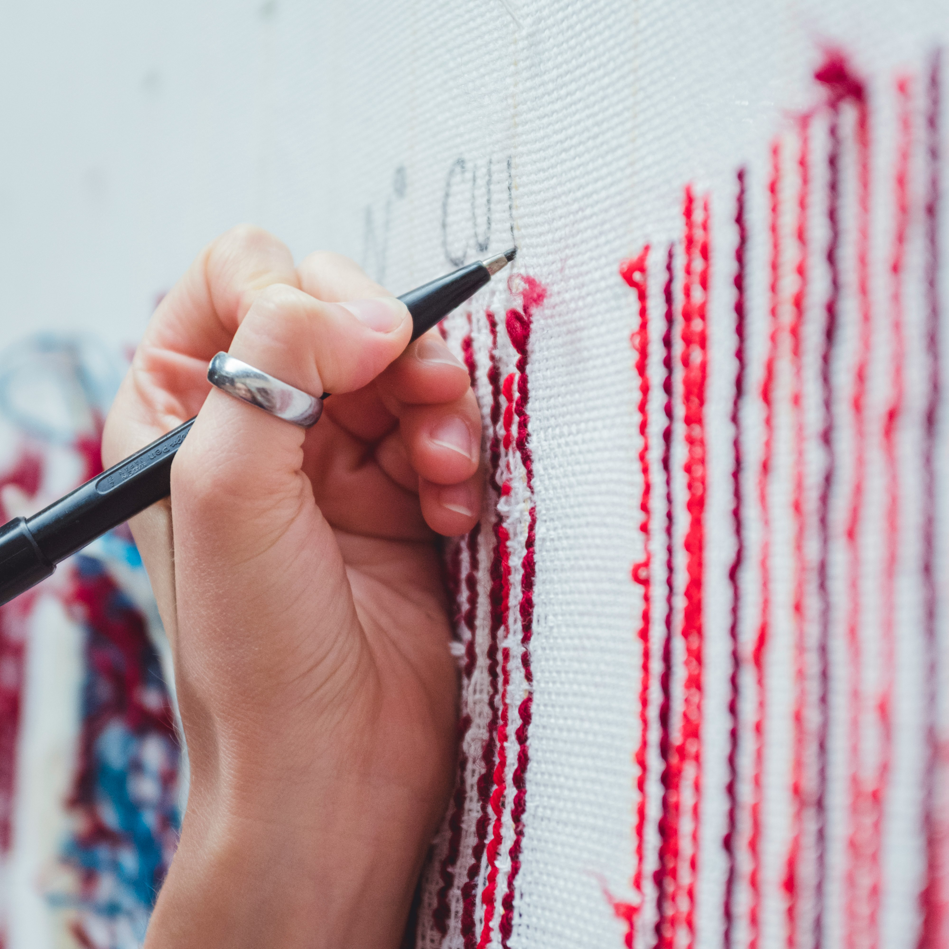 person holding black pen and red and white textile